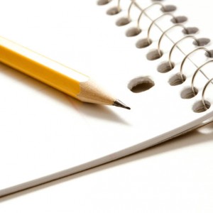 Sharp pencil placed on open spiral bound notebook.