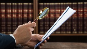 Cropped image of lawyer examining documents with magnifying glass in courtroom